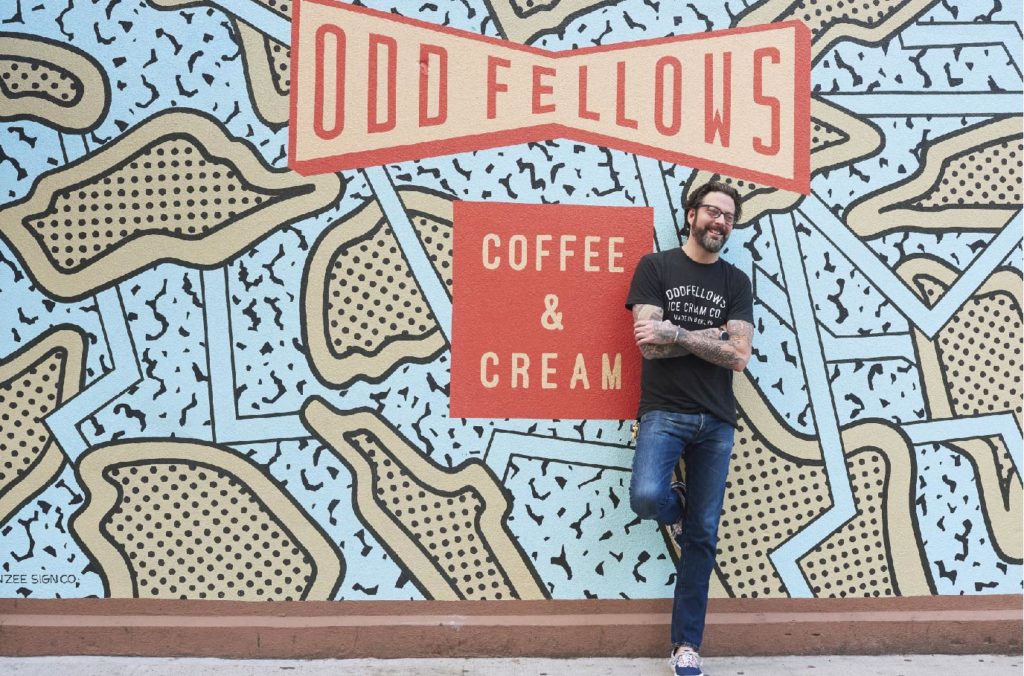 Sam Mason standing in front of OddFellows mural
